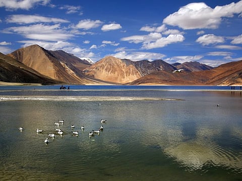 In this June 17, 2016, file photo, an Indian tourist rides on a horse back at the Pangong Lake high up in Ladakh region of India. Tensions along the China-India border high in the Himalayas have flared again in recent weeks. Indian officials say the latest row began in early May when Chinese soldiers entered the Indian-controlled territory of Ladakh at three different points, erecting tents and guard posts.