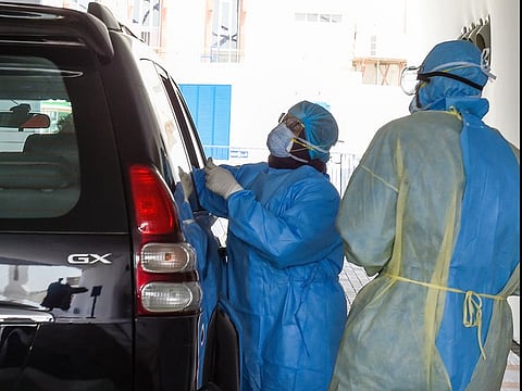 Paramedics collect swab samples at a coronavirus drive-through screening center by Dubai Health Authority at Al Nasr Club in Dubai.