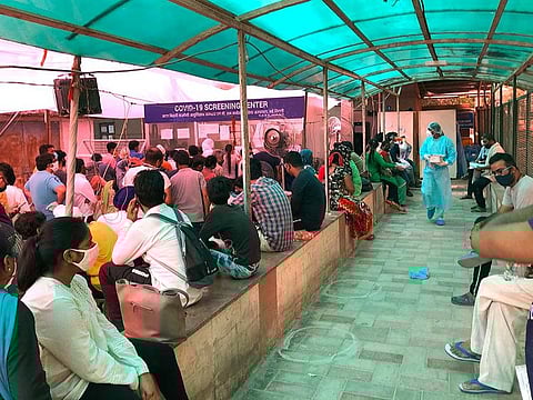 In this Wednesday, June 10, 2020 photo, people stand in a queue for COVID 19 screening at a coronavirus designated hospital in New Delhi, India.