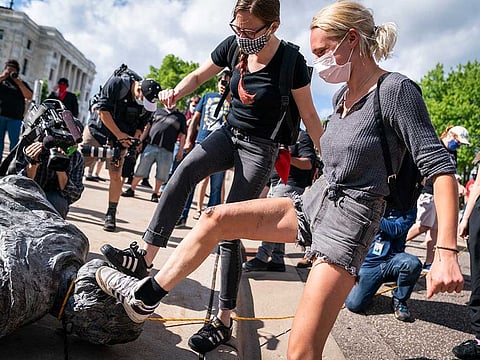 People take turns stomping the Christopher Columbus statue after it was toppled in front of the Minnesota State Capitol in St. Paul, Minn., on Wednesday, June 10, 2020.