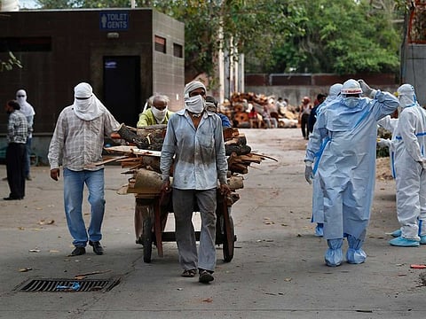 Workers push a handcart carrying wood for the funeral pyre of victims of COVID-19, at a crematorium in New Delhi.