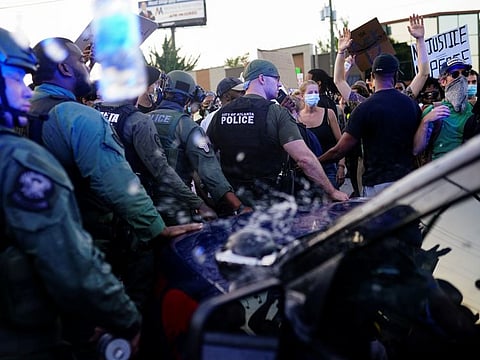 Police officers escort a police SUV from a crowd of protesters while bottles of water are thrown at them during a rally against racial inequality and the police shooting death of Rayshard Brooks, in Atlanta, Georgia, US, June 13.
