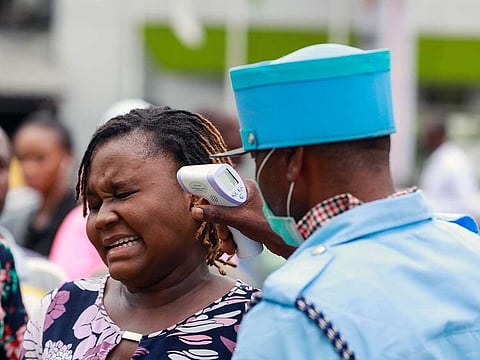 A security guard uses a thermal scanner to check a woman's temperature as she enters the Tejuoso shopping complex at the Yaba market, amid the coronavirus disease (COVID-19) outbreak, in Lagos, Nigeria March 23, 2020.