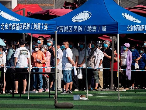 People who live near or have visited the Xinfadi Market, a wholesale food market where a new COVID-19 coronavirus cluster has emerged, wear facemasks while queueing for testing at the Guang'an sports centre in Beijing on June 16, 2020.