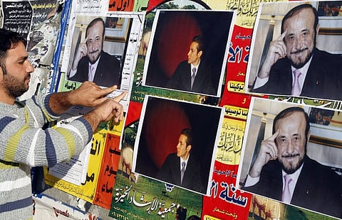 In this file photo taken on December 6, 2007 a member of the Alawite community pastes on a wall, in the northern Lebanese city of Tripoli pictures of Syrian opposition leader Rifaat Al Assad.