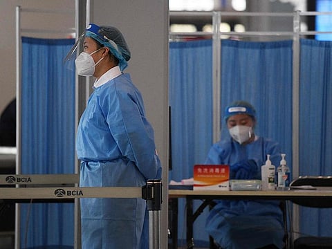 Workers wearing protective clothing wait to check the temperature of passengers entering the airport in Beijing.