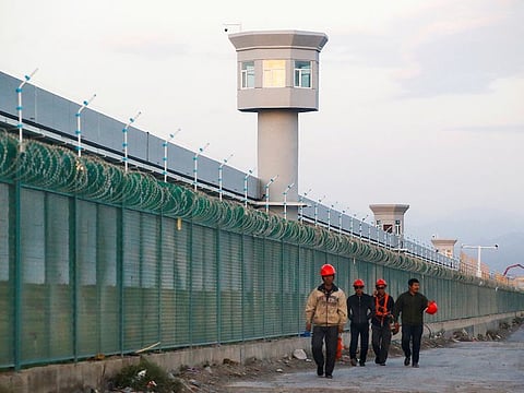 Workers walk by the perimeter fence of what is officially known as a vocational skills education centre in Dabancheng in Xinjiang Uighur Autonomous Region, China September 4, 2018.