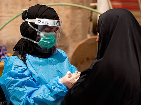 A medical worker prepares to take a swab from a woman being tested for COVID-19 coronavirus disease, in the 5-Miles district of Iraq's southern Basra.