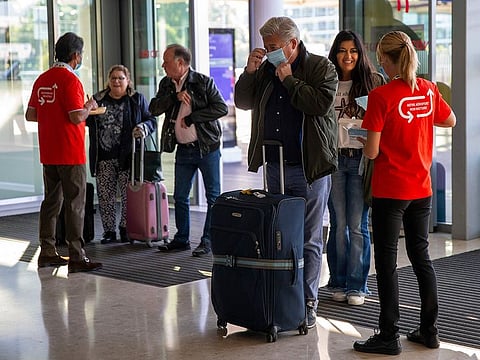 Staff members of Geneva Airport offer face masks to passengers in the check-in hall of the terminal in Geneva, Switzerland, during the lifting of coronavirus COVID-19 lockdown regulations.