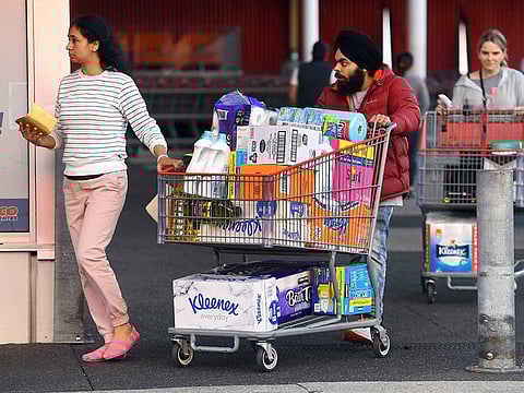People leave a Costco outlet with a trolley full of toilet paper and cleaning products as fears of a second wave of COVID-19 have sparked a rush on some supermarket items in Melbourne on June 24, 2020.