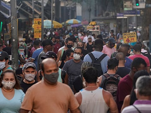 Pedestrians, some wearing protective face masks, walk through a street market in downtown in Rio de Janeiro, Brazil, Thursday, June 25, 2020.
