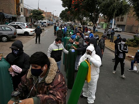 People wearing face masks wait with oxygen tanks at a private distributor that recharges tanks, amid the spread of the coronavirus disease (COVID-19), in Lima, Peru June 25, 2020.