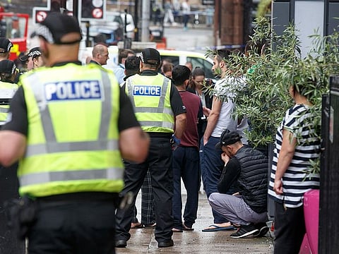 Members of the public within the police cordon react as police and emergency services respond at the scene of a fatal stabbing incident at the Park Inn Hotel in central Glasgow on June 26, 2020.