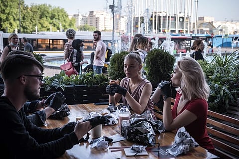 Customers wearing gloves eat burgers on the terrace of Black Star Burger in Moscow on June 16, 2020. Status-conscious fast-food joints across Eastern Europe have offered their diners disposable gloves for years and the idea may find a wider audience in the pandemic era. (Sergey Ponomarev/The New York Times)