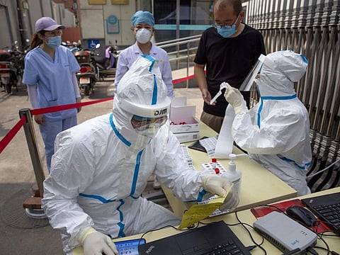 Workers wearing protective suits register people for coronavirus tests at a community health clinic in Beijing on June 28.