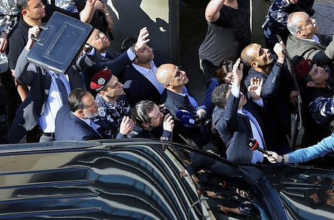 In this March 19, 2017 file photo, bodyguards protect then Lebanese Prime Minister Saad Hariri, center left, from water bottles thrown by demonstrators, in downtown Beirut, Lebanon. An explosion occurred earlier in June 2020 near the convoy of Hariri when he was on a visit in a mountainous region in Lebanon's eastern Bekaa Valley.