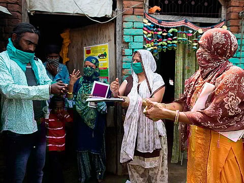 In this picture taken on June 9, 2020, Accredited Social Health Activist (ASHA) workers (3R to R) Alka, Nirmala and Meenkashi demonstrate how to wash hands to a migrant worker who returned recently to the village, during a door-to-door survey to check on residents after the government eased a nationwide lockdown imposed as a preventive measure against the COVID-19 coronavirus, in Bahadarpur village in Meerut district.
