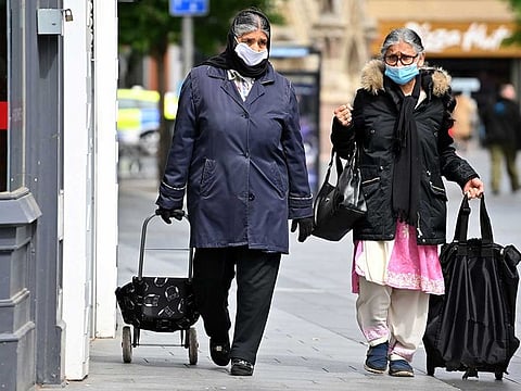Shoppers wearing PPE (personal protective equipment), of a face mask or covering as a precautionary measure against spreading COVID-19, walk in the city centre of Leicester, central England, on June 30, 2020. Britain on Monday reimposed lockdown measures on a city hit by an outbreak of coronavirus, in the first big test of Prime Minister Boris Johnson's "whack-a-mole" strategy to control the disease while getting the economy moving again.