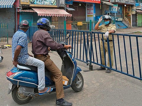 A policeman sends motorists back as he stands guard near a barricaded commercial street lined with shops and business establishments, which was closed by the authorities in Bangalore on June 25, 2020.