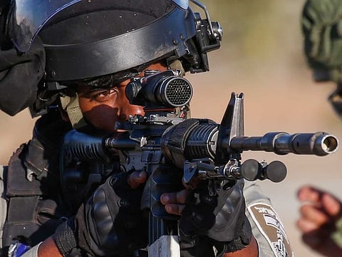 An Israeli soldier aims his weapon at Palestinian protesters following a rally against Israel's West Bank annexation plans, in the Jordan Valley village of Fasayil on June 24, 2020.