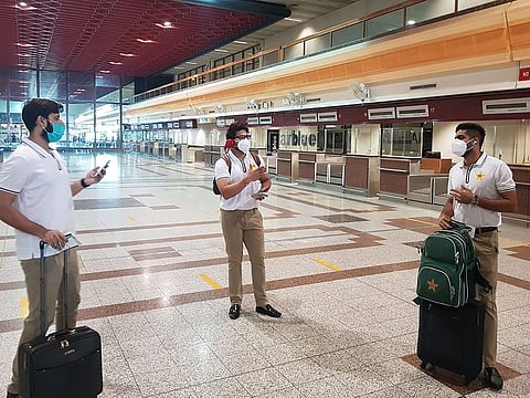 File photo: Pakistan cricketers Babar Azam (R), Imad Wasim (L) and Imam-ul-Haq (C) wearing facemasks arrive at the Allama Iqbal International airport before their departure to England, in Lahore.
