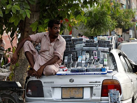 A man waits for customers to sell them television remote controls from the back of a parked car, after Pakistani authorities re-imposed smart lockdowns in some selected areas, in Karachi, Pakistan