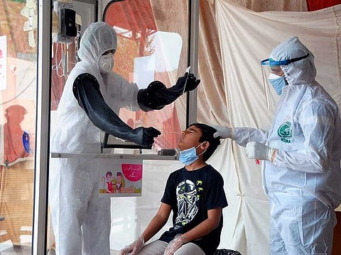 Health workers take a nasal swab sample during a testing and screening operation for the new coronavirus, in Hyderabad, Pakistan on Friday, June 26, 2020.