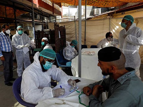 A paramedic wearing protective gear takes notes of a man's health history before taking a nose-swab sample to be tested for the coronavirus disease (COVID-19), in Karachi, Pakistan June 27, 2020.