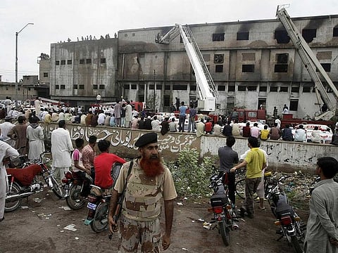 People gather at the site of burnt garment factory in Karachi, Pakistan, September 12, 2012. Fires broke out at two factories in Pakistan, killing more than 260 people.
