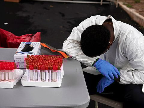 Overheated, a healthcare worker takes a break as people wait in their vehicles in long lines for the coronavirus disease (COVID-19) testing in Houston, Texas, U.S., July 7, 2020.