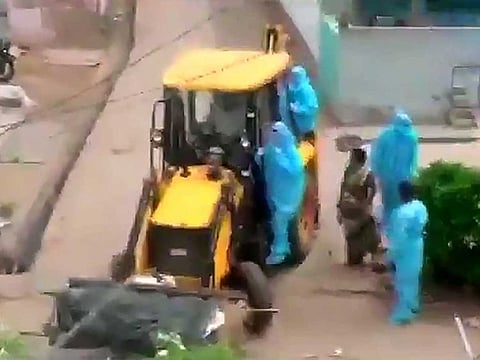 The body of a 70-year-old person who died of COVID-19 being disposed of using a proclainer by Palasa municipal authorities, in Srikakulam on Saturday, June 27. Andhra Pradesh has seen more cases of bodies being dumped by earthmovers.
