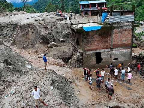 Residents and rescue workers inspect the area outside a house damaged by a landslide and the swell of the Thado-Koshi river due to heavy rains in Jambu village of Sindhupalchok district, some 80 kms northeast of Kathmandu on July 9, 2020.
