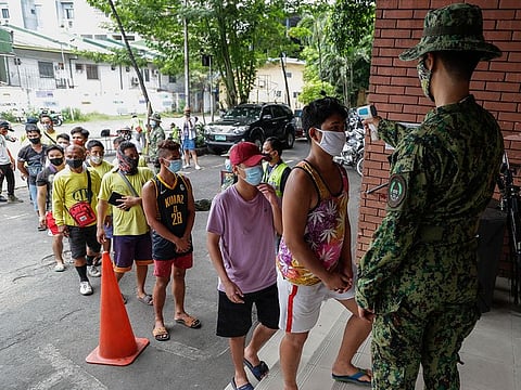 Men who were arrested for violating quarantine health protocols have their temperatures checked at the Amoranto Sports Complex in Manila, Philippines.
