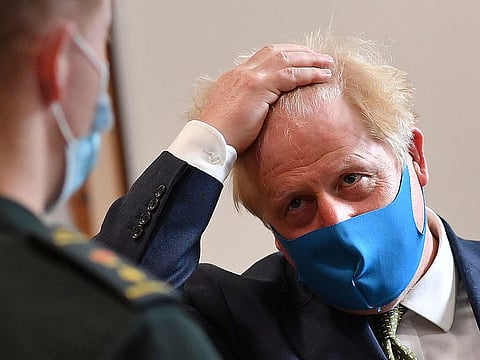 Britain's Prime Minister Boris Johnson, wearing a face mask, talks with a paramedic during a visit to the headquarters of the London Ambulance Service NHS Trust