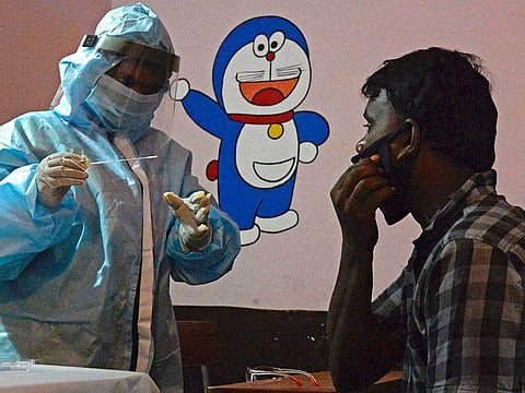 A health worker wearing personal protective equipment (PPE) gear collects a swab sample of a resident at a free testing centre for the COVID-19 coronavirus, at a government primary school in Secunderabad, the twin city of Hyderabad on July 14, 2020.