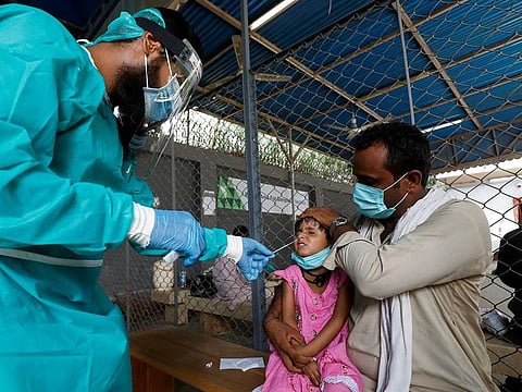 A paramedic wearing protective gear takes a nasal swab from a child, to be tested for the coronavirus disease (COVID-19), in Karachi, Pakistan July 13, 2020.