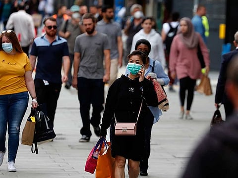 Shoppers walk along Oxford Street in London, Tuesday, July 14, 2020. Britain's government is demanding people wear face coverings in shops as it has sought to clarify its message after weeks of prevarication amid the COVID-19 pandemic.