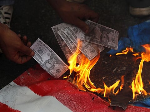 In this July 10, file, photo, a supporter of a communist group burns representation of US currency, during a protest against US interference in Lebanon's affairs, near the US embassy in Aukar northeast of Beirut.