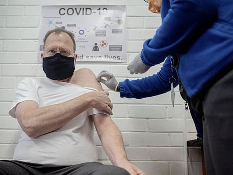 Professor Martin Veller (L), the Dean of the Faculty of Health Sciences at the University of the Witwatersrand (Wits University), receives an experimental vaccine for COVID-19 coronavirus at the Respiratory & Meningeal Pathogens Research Unit (RMPRU) at Chris Hani Baragwanath Hospital in Soweto on July 14, 2020. - Six senior clinicians in the Faculty of Health Sciences at Wits University have volunteered to participate in South Africas first COVID-19 vaccine trial. (Photo by Luca Sola / AFP)