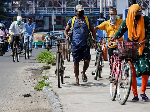 People wearing face masks cross a bridge with their cycles in Kolkata, India, Tuesday, July 14, 2020. Several Indian states imposed weekend curfews and locked down high-risk areas as the number of coronavirus cases surged past 900,000 on Tuesday.
