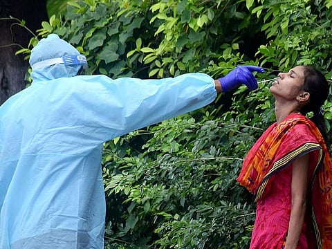 A health worker wearing PPE kit collects the swab sample of a woman for COVID-19 test at a collection centre, during the lockdown, in Patna on Thursday, July 16, 2020.