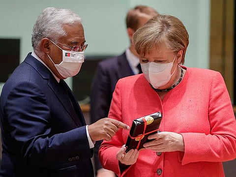 German Chancellor Angela Merkel, right, receives a gift from Portugal's Prime Minister Antonio Costa during a round table meeting at an EU summit in Brussels, Friday, July 17, 2020. Leaders from 27 European Union nations meet face-to-face on Friday for the first time since February, despite the dangers of the coronavirus pandemic, to assess an overall budget and recovery package spread over seven years estimated at some 1.75 trillion to 1.85 trillion euros.