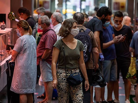 Customers buy fish and meat at a market in Barcelona, Spain.