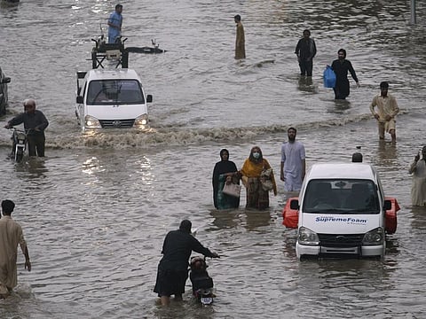 People wade through a flooded road caused by heavy rainfall in Karachi, Pakistan.