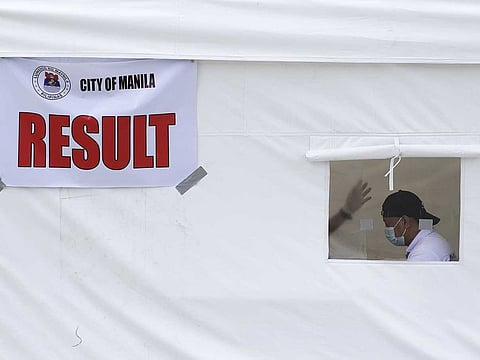 A man wears a face mask inside a tent at a free COVID-19 drive-thru testing facility in Manila, Philippines.