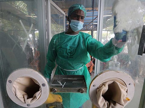 An employee cleans a booth at a testing and screening facility for the new coronavirus, in a hospital in Karachi, Pakistan, Friday, July 17, 2020.