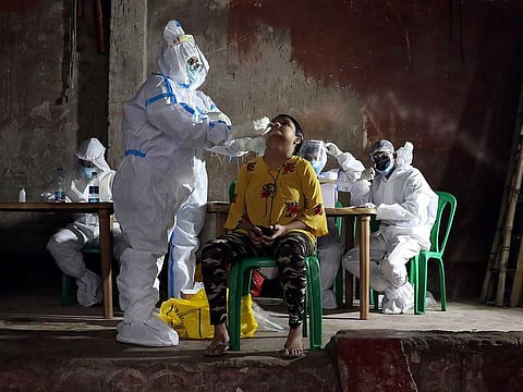 A healthcare worker wearing personal protective equipment (PPE) takes a swab from a woman to test for the coronavirus disease (COVID-19) in Kolkata, India, July 23, 2020.