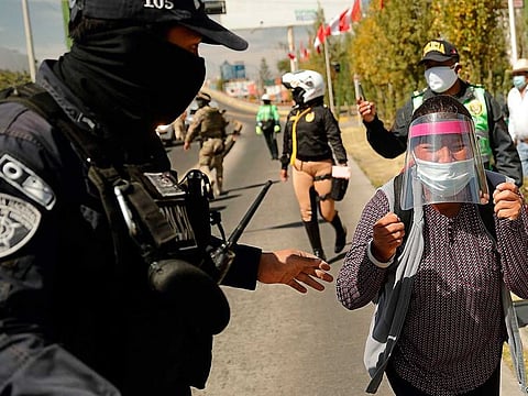 A policeman stops Celia Capira Mamani, while attempting to reach the car of Peru’s President Martin Vizcarra to demand medical attention for her husband Adolfo Mamani Tacuri, infected with the novel coronavirus COVID-19, during the latter’s visit to the Honorio Delgado Hospital in the southern Andean city of Arequipa on July 19, 2020.