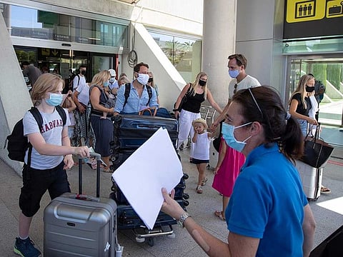 Tourists walk with their luggage outside the airport upon their arrival to Palma de Mallorca on July 27, 2020. Tour operator TUI has cancelled all British holidays to mainland Spain from today until August 9, after the UK government's decision to require travellers returning from the country to quarantine.