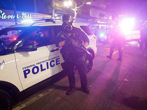A federal officer stands by a police vehicle during a Black Lives Matter protest early Saturday, July 25, 2020, in Portland, Ore.